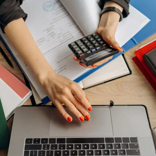 Woman holding a calculator and working on laptop